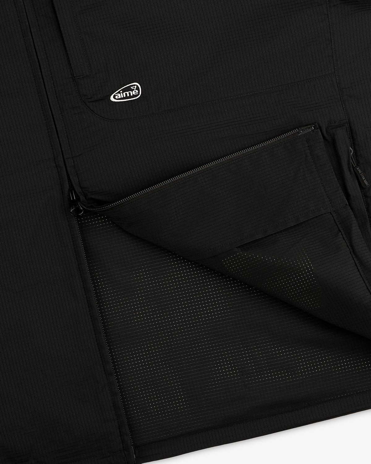 Close-up of the ALD Golf Lightweight Tips Windbreaker’s black pocket, half-zipped, with logo patch above.