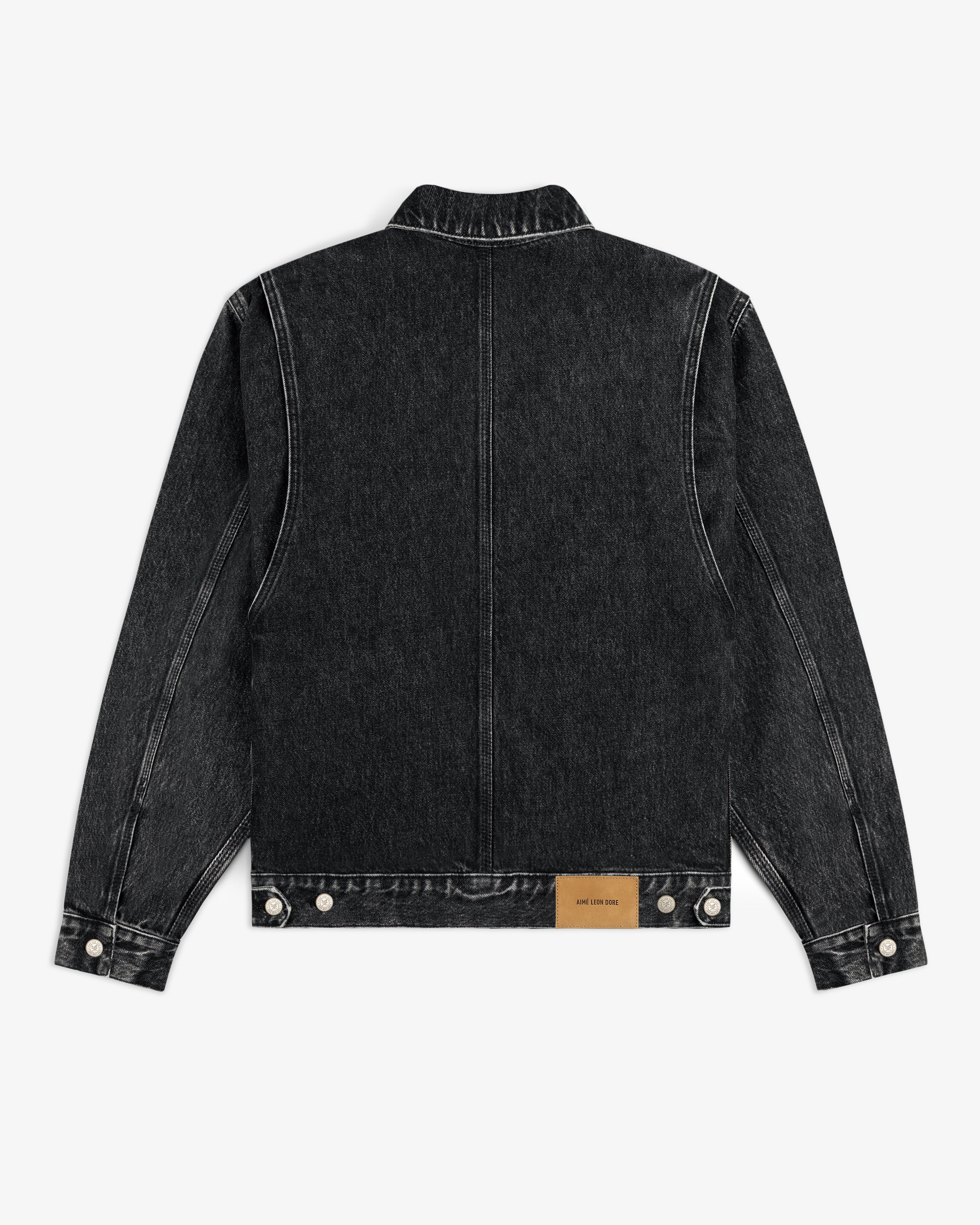 Back view of Denim Trucker Jacket in black with white stitching and a tan leather patch near the bottom hem.