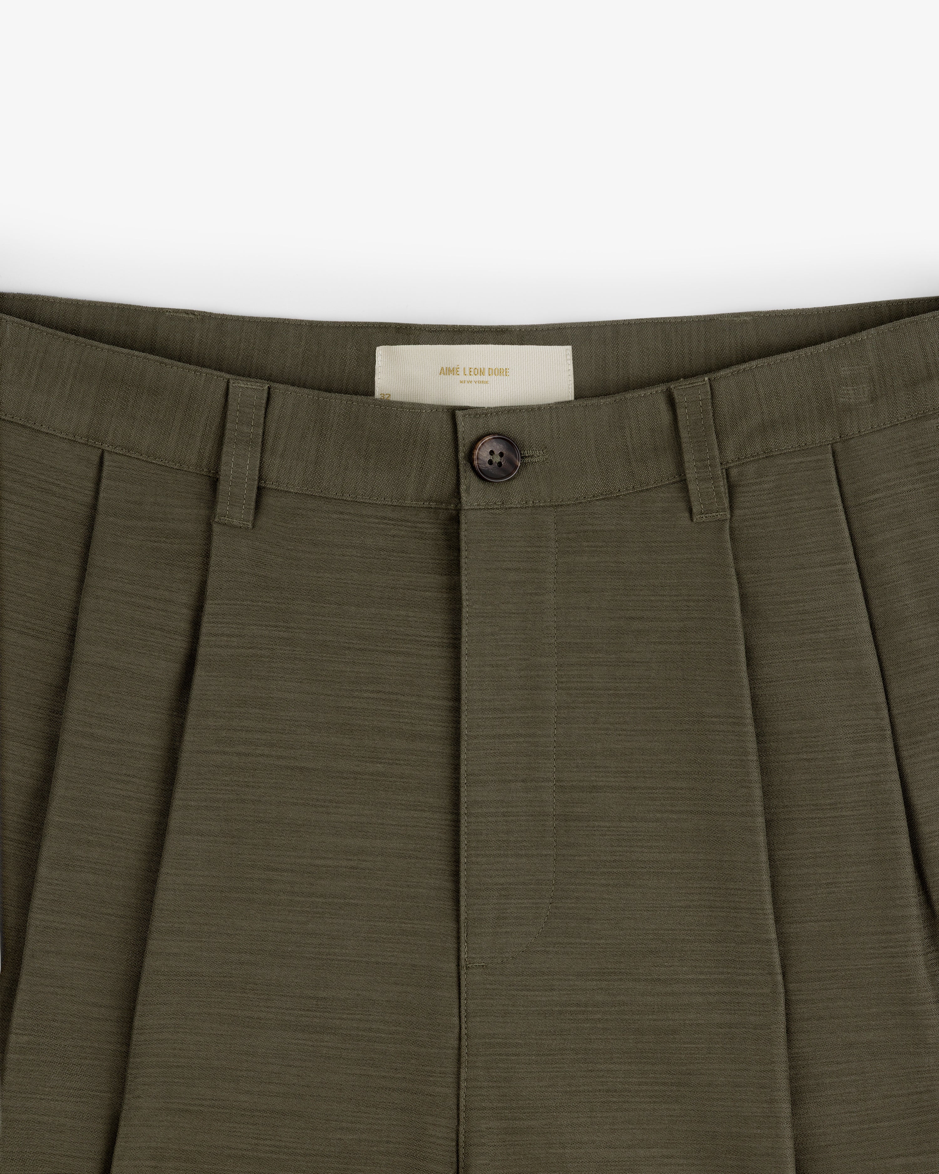 Close-up of Double Pleated Pant in olive green, featuring button closure and belt loops.