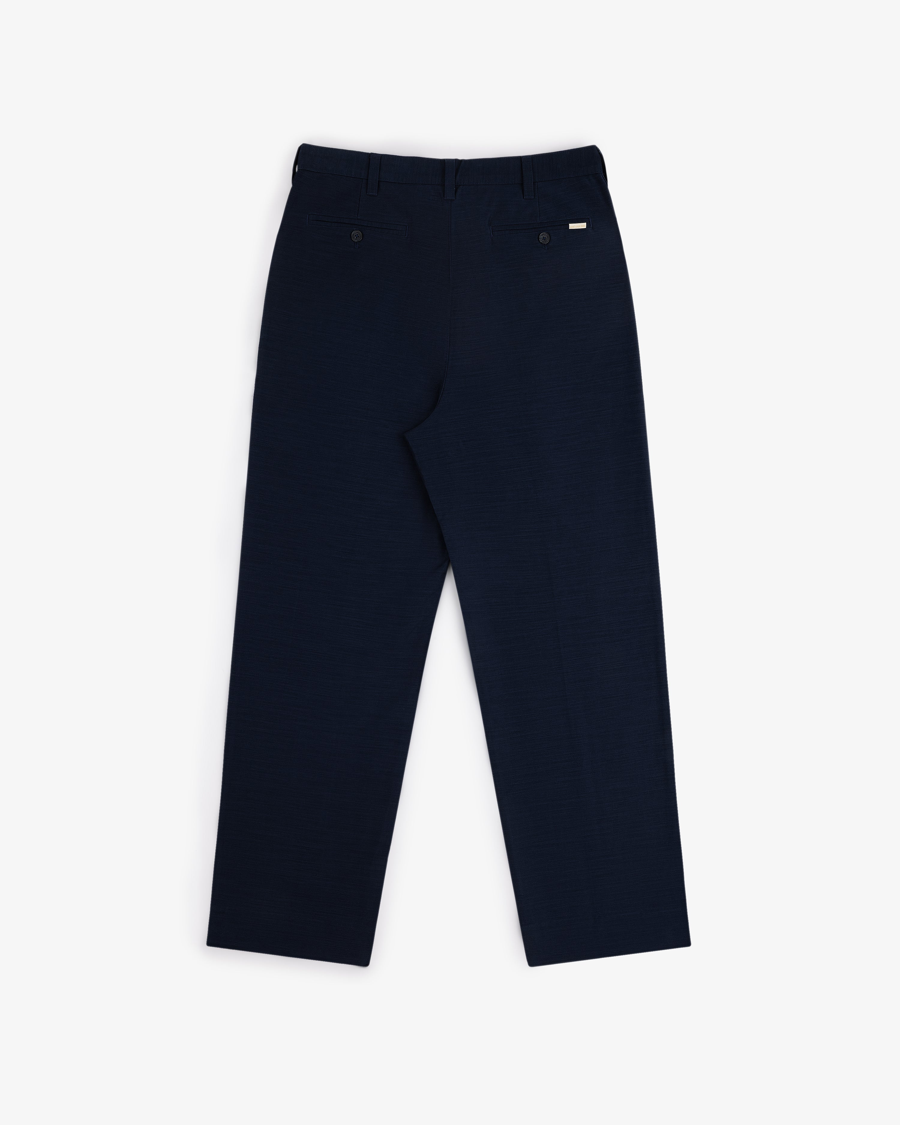 Back view of Double Pleated Pant in dark navy with two back pockets and belt loops, laid flat on white background.