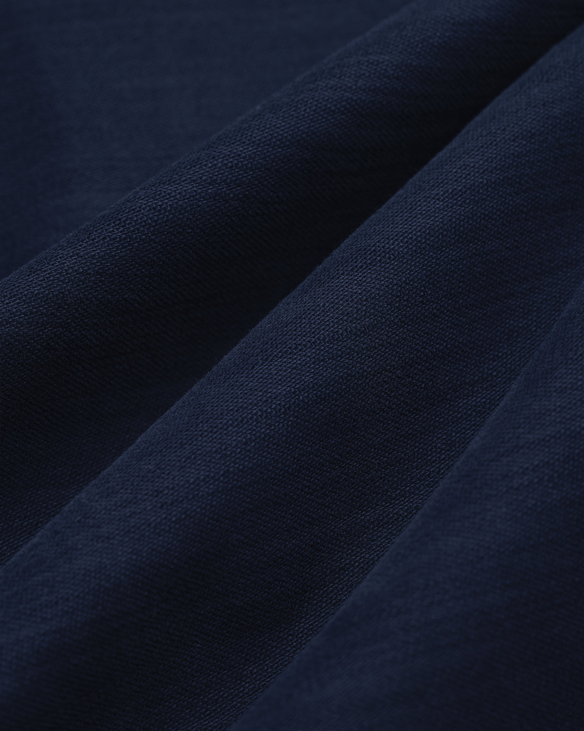 Close-up of Double Pleated Pant in dark blue, showing visible weave texture and soft diagonal folds.