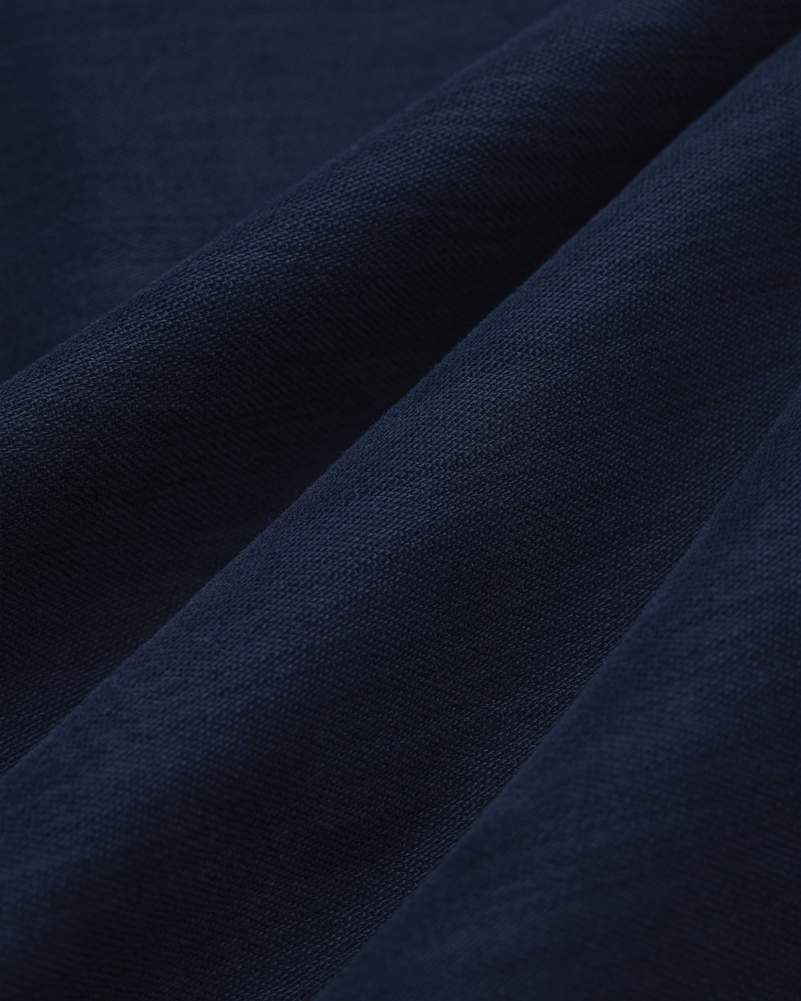 Close-up of Double Pleated Pant in dark blue, showing visible weave texture and soft diagonal folds.