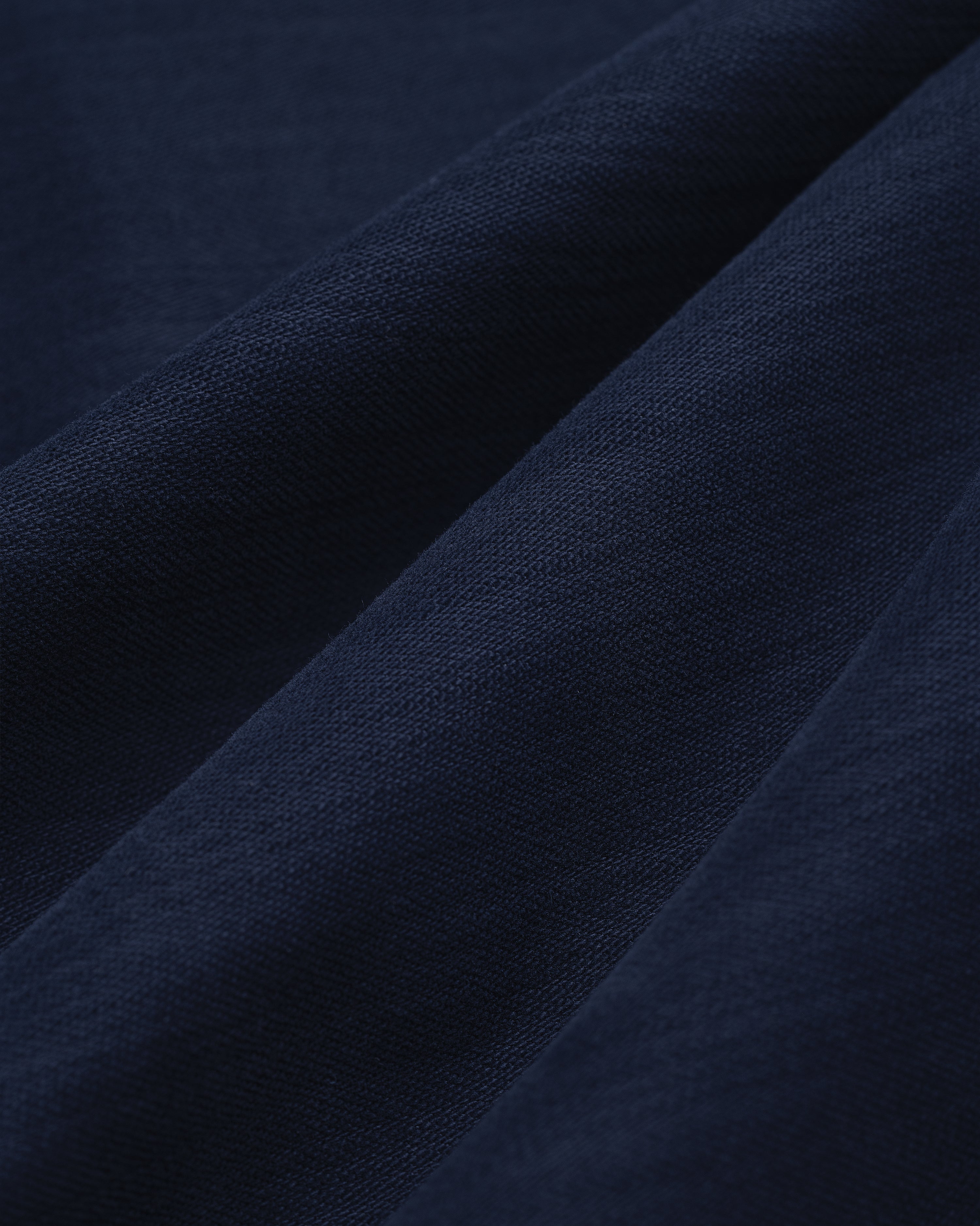 Close-up of Double Pleated Pant in dark blue, showing visible weave texture and soft diagonal folds.