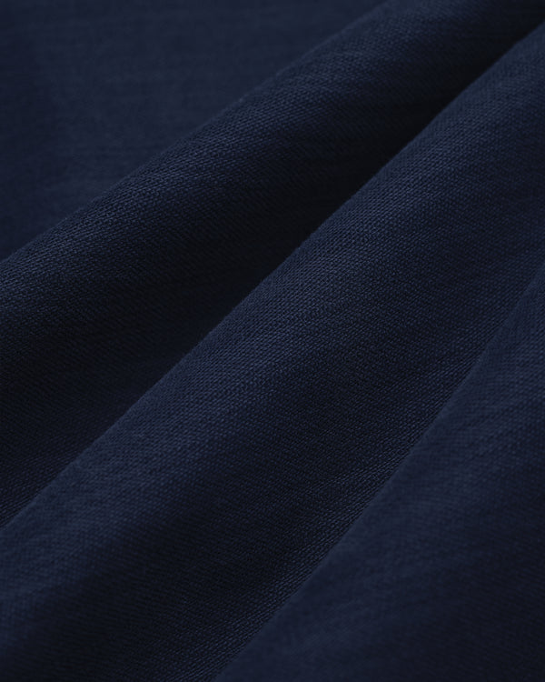 Close-up of Double Pleated Pant in dark blue, showing visible weave texture and soft diagonal folds.