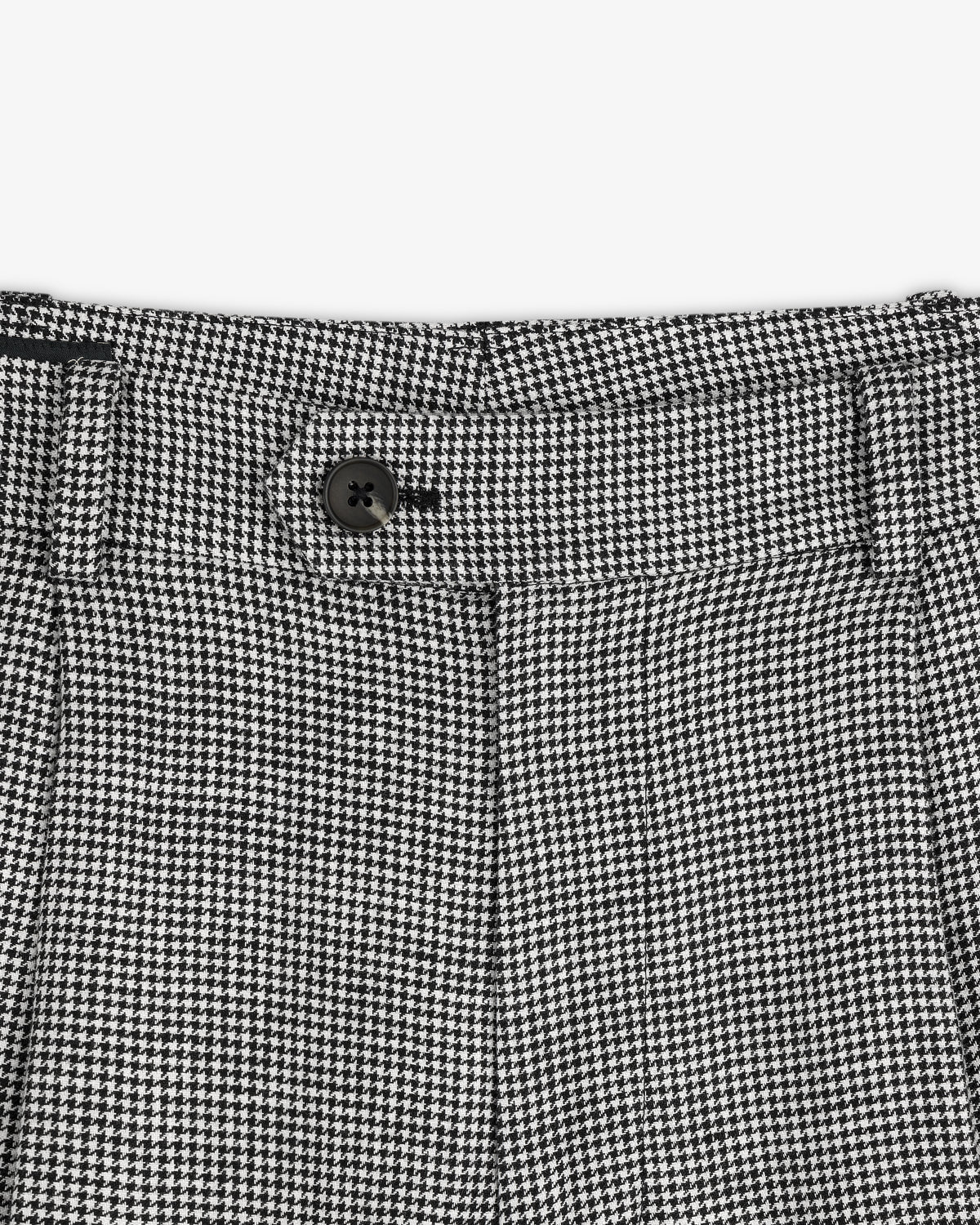 Close-up of the waistband on Houndstooth Pleated Trouser featuring a black button and belt loops.