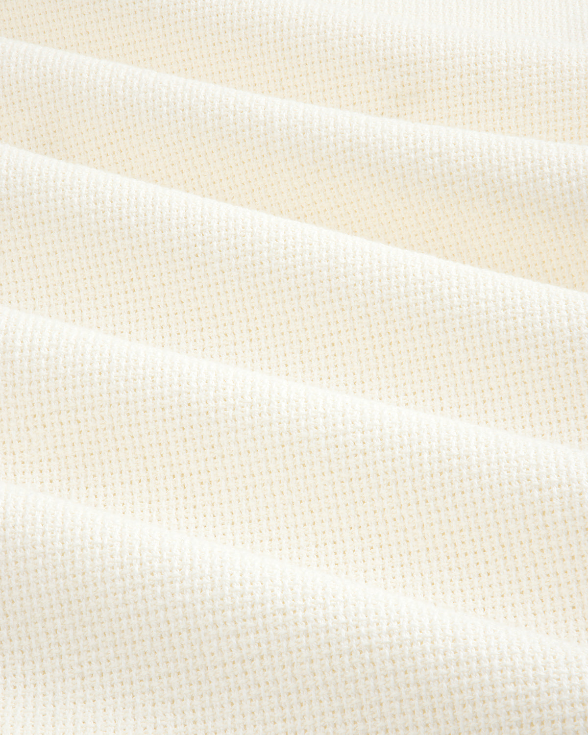 Close-up of cream-colored, textured fabric from the Wide Leg Shore Pant, featuring a subtle grid pattern and soft folds.
