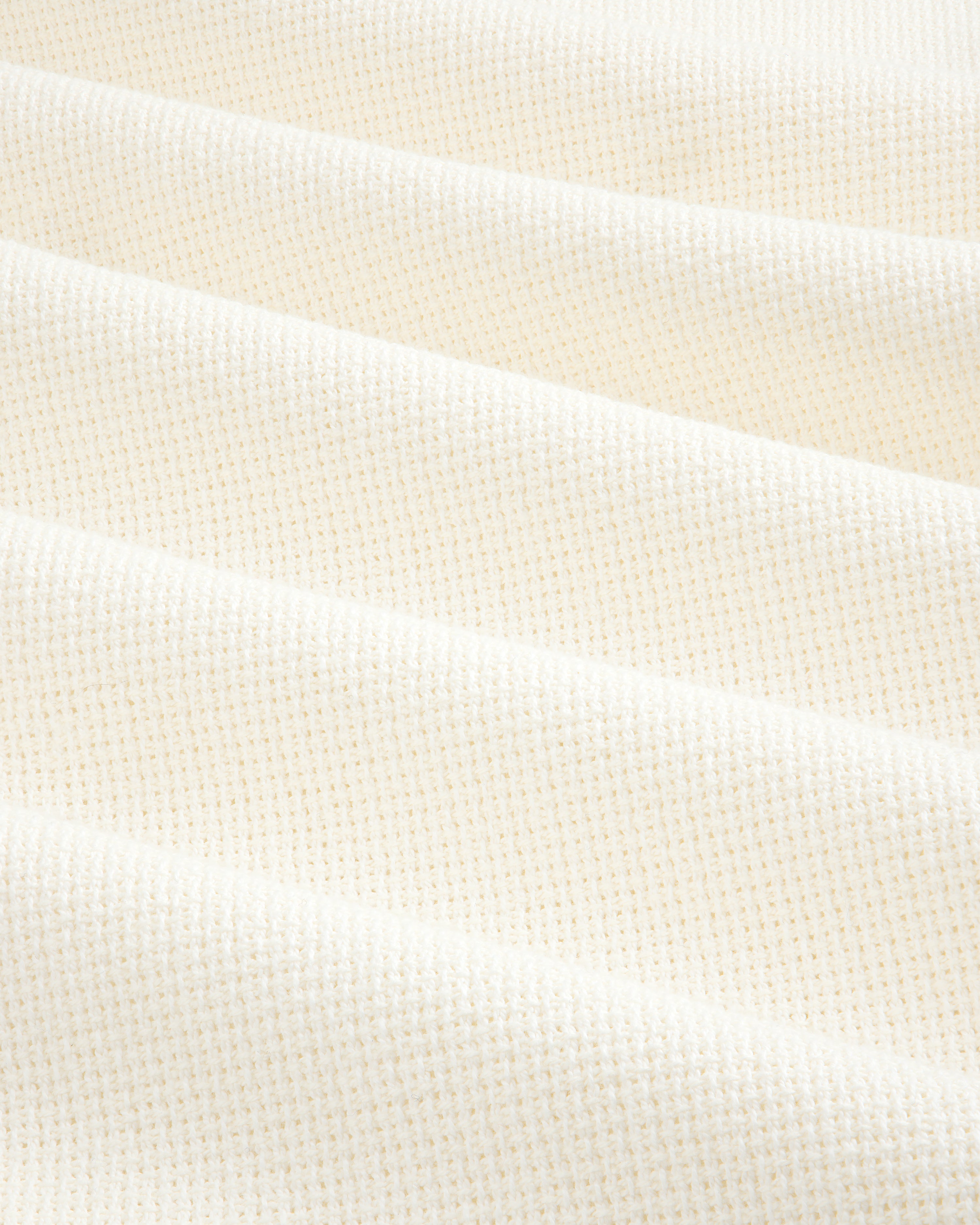 Close-up of cream-colored, textured fabric from the Wide Leg Shore Pant, featuring a subtle grid pattern and soft folds.