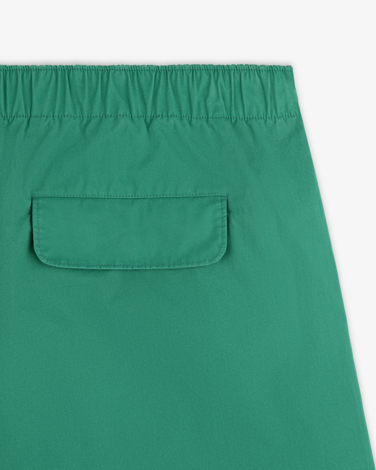 Close-up of Washed Cotton Windbreaker Pant in green, featuring an elastic waistband and a flap back pocket.