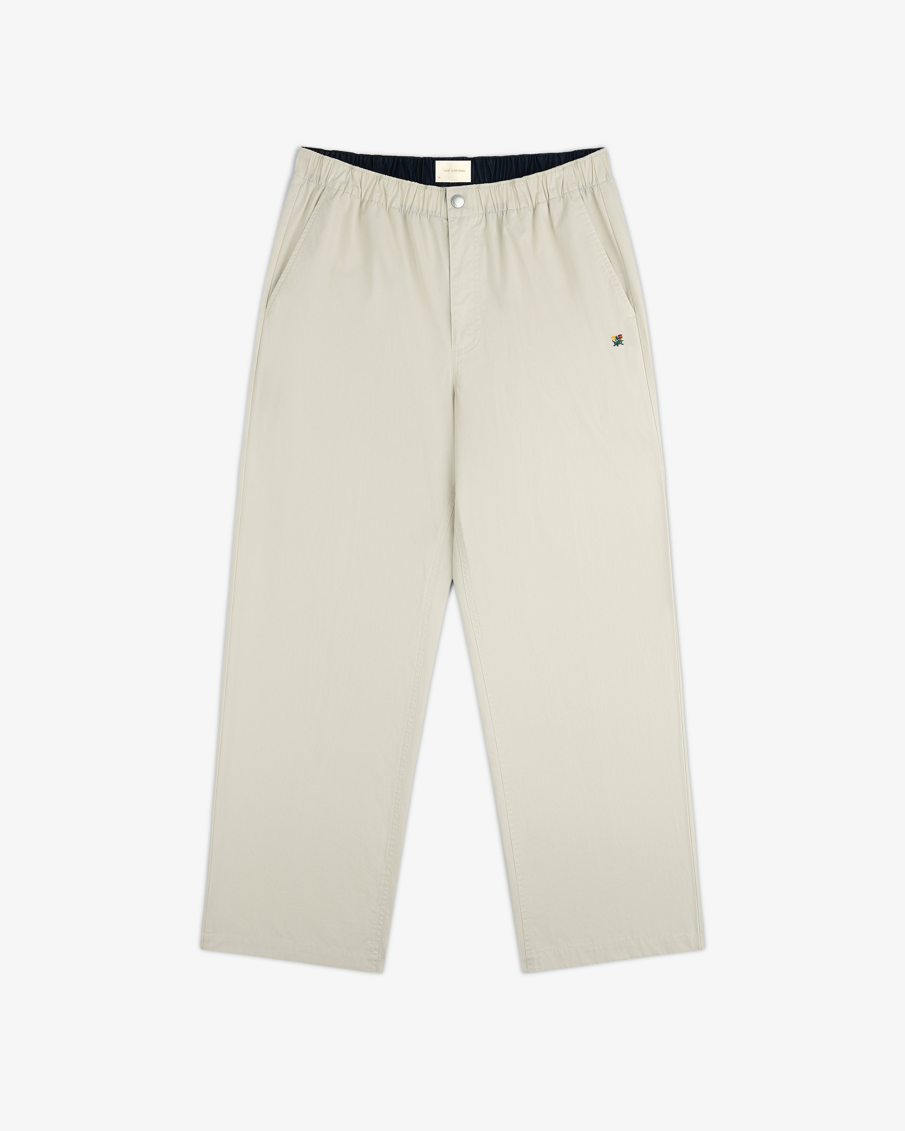 Washed Cotton Windbreaker Pant in beige with wide legs, side pockets, elastic waist, and a small logo near the left pocket.