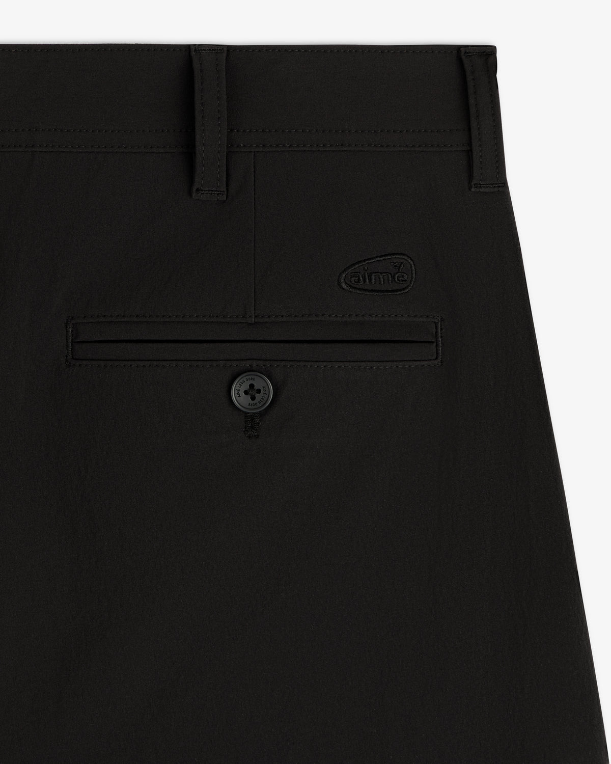 Close-up of the ALD Golf Cordura Double Pleated Pant’s back pocket with button and “dime” logo above it.