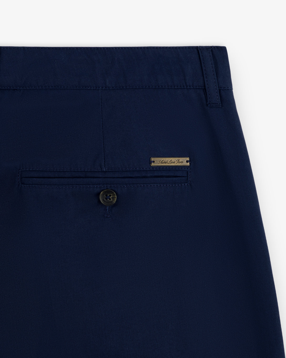 Close-up of the back pocket with button and metal label on Lightweighted Pleated Cotton Trouser in navy blue.