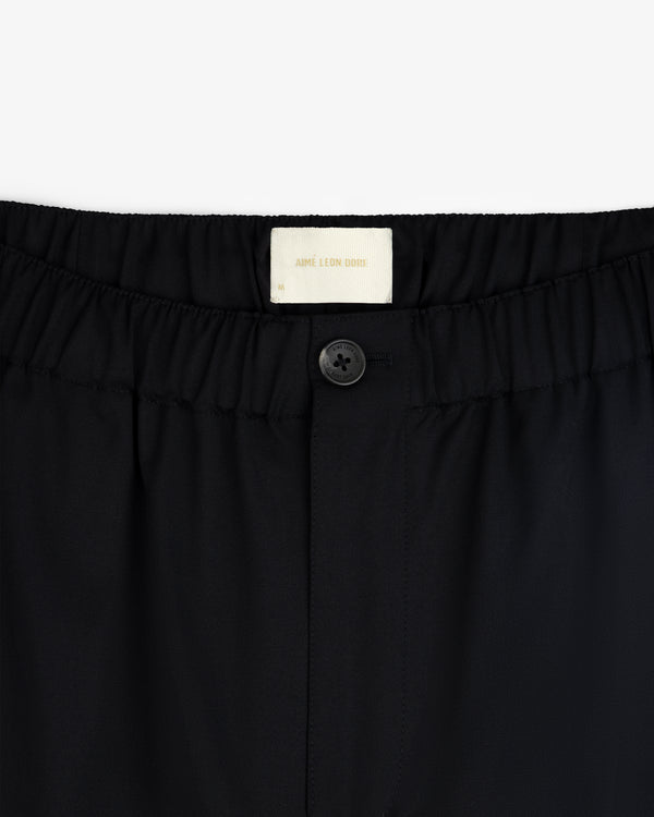 Close-up of Elasticated Waist Gabardine Trouser in black with a button closure and visible Aimé Leon Dore label.