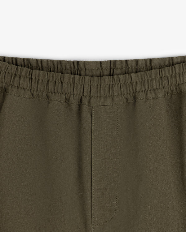 Close-up of Linen Leisure Pant in olive green with elastic waistband and center seam on white background.