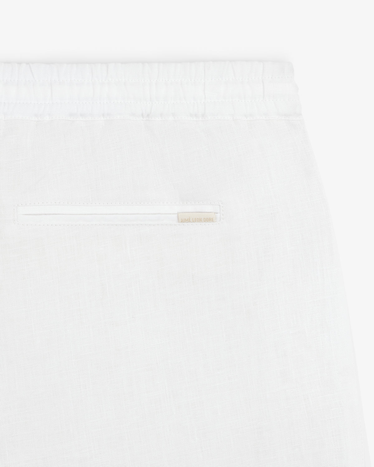 Close-up of Linen Leisure Pant in white, featuring an elastic waistband and a single back slit pocket.