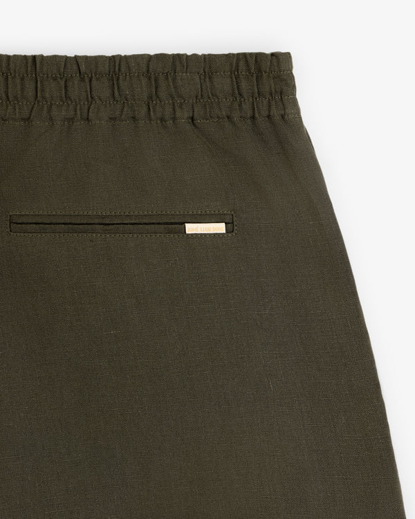 Close-up of Linen Leisure Short in olive green with elastic waistband and back pocket featuring a metallic brand tag.