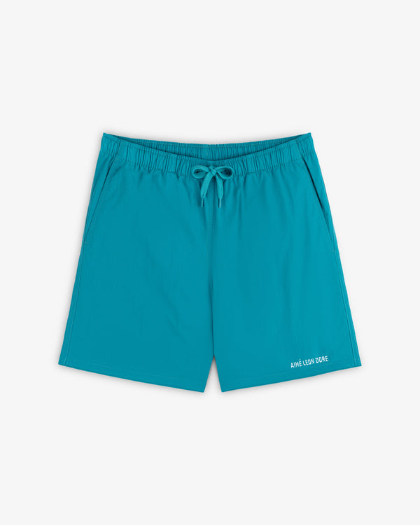 Logo Swim Short in bright turquoise with elastic waistband, drawstring, side pockets, and logo text on the hem.