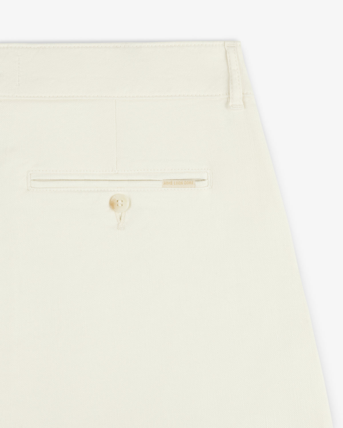 Close-up of the back pocket of Pleated Linen Blend Bermuda Short in cream with a button and beige label above the pocket.