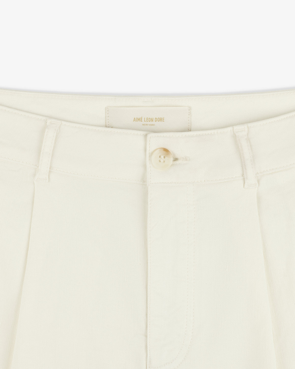 Close-up of Pleated Linen Blend Bermuda Short in cream with a single button and belt loops at the waistband.