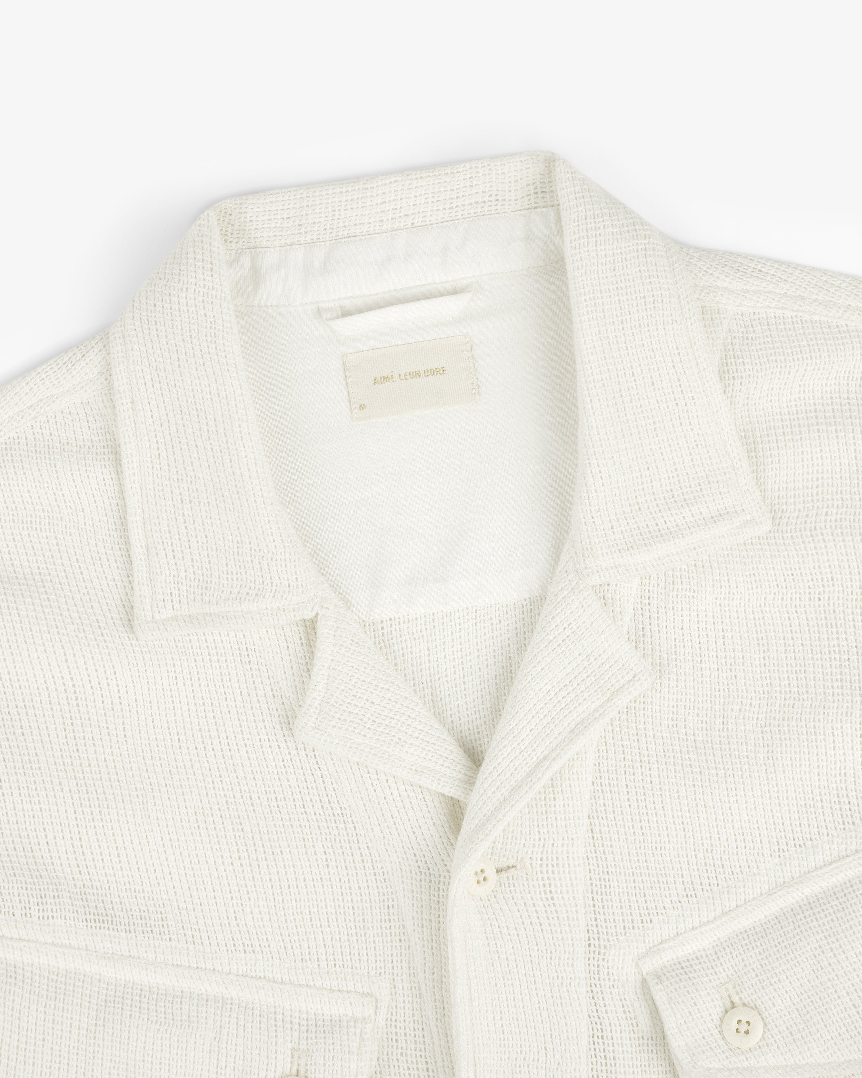 Cream-colored Mesh Jungle Shirt with collar, buttons, and front pockets on a white background.