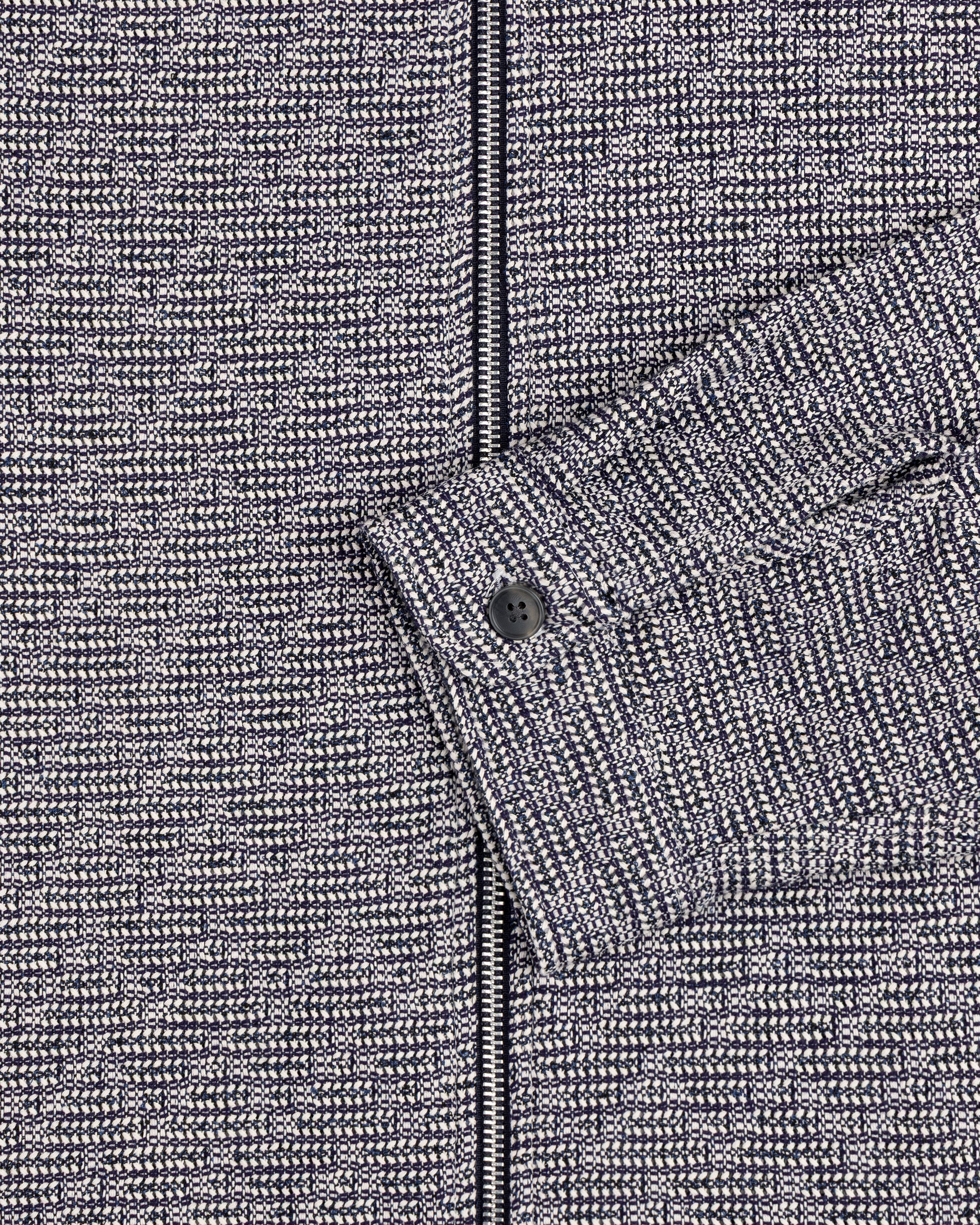 Close-up of the Textured Zip Shirt: gray and black patterned fabric with a sleeve and black button.
