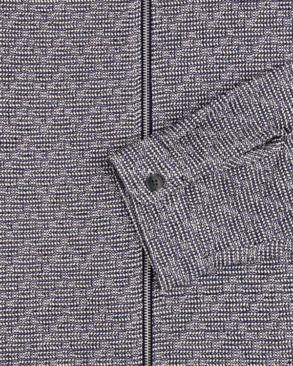 Close-up of the Textured Zip Shirt: gray and black patterned fabric with a sleeve and black button.