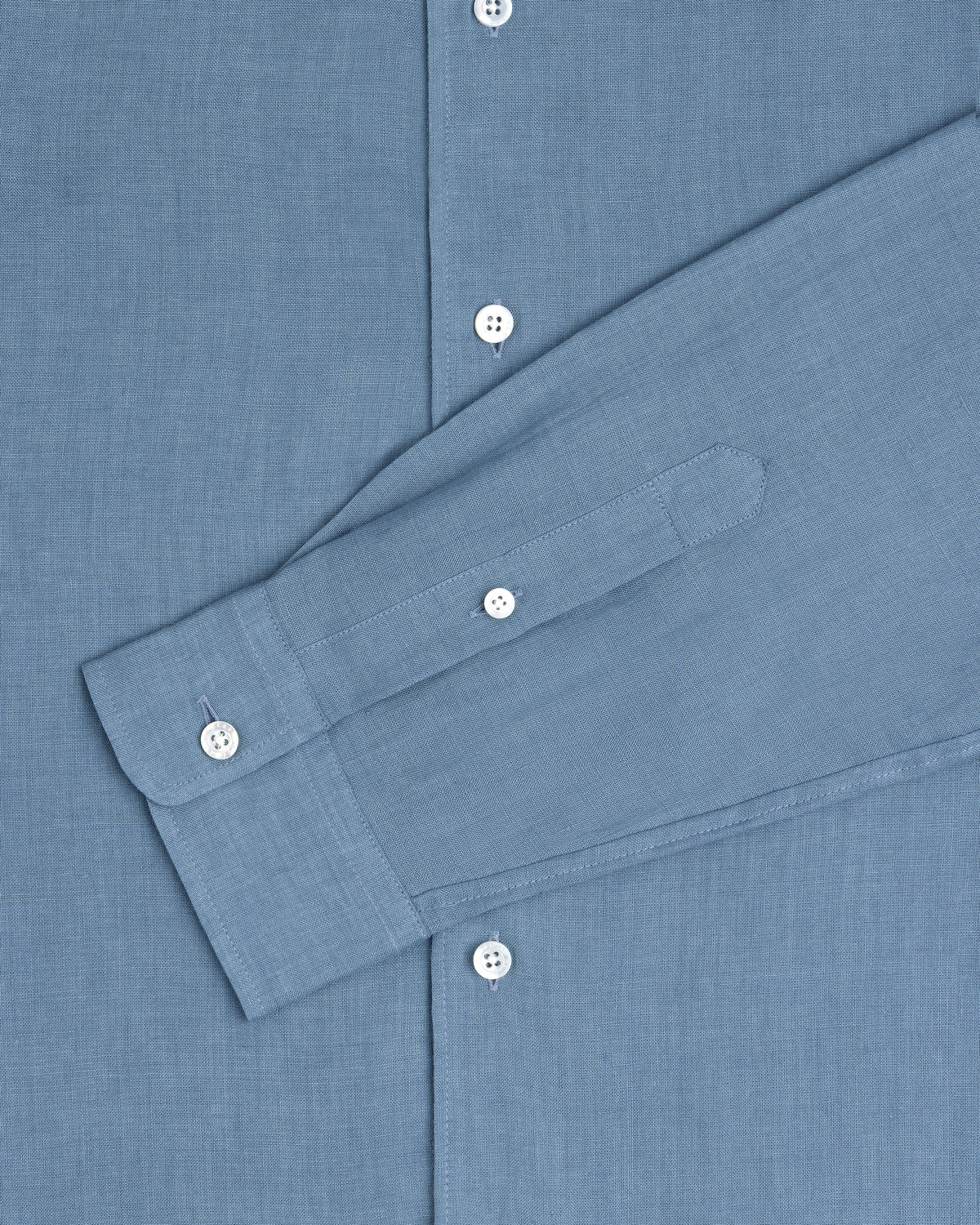 The Long-Sleeve Linen Shirt in blue features white buttons and is shown from chest to cuff.