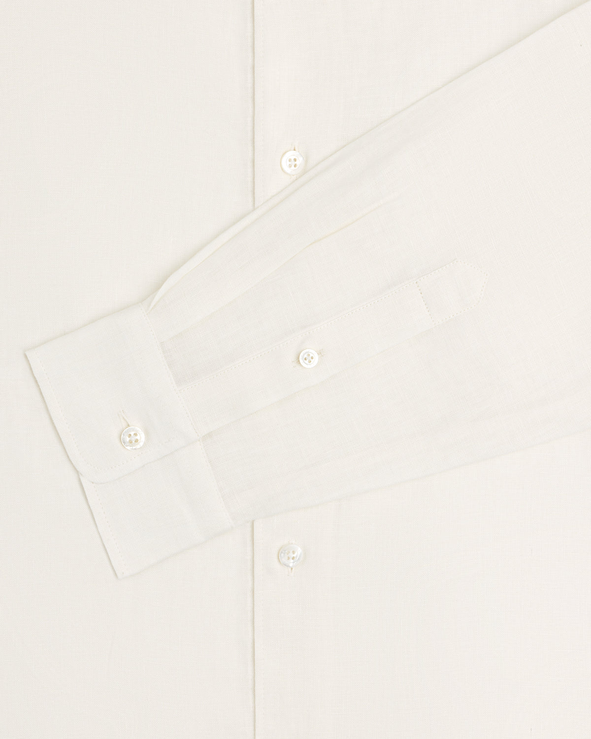A close-up of the Long-Sleeve Linen Shirt displays its sleeve, cuff, and buttons against a light background.