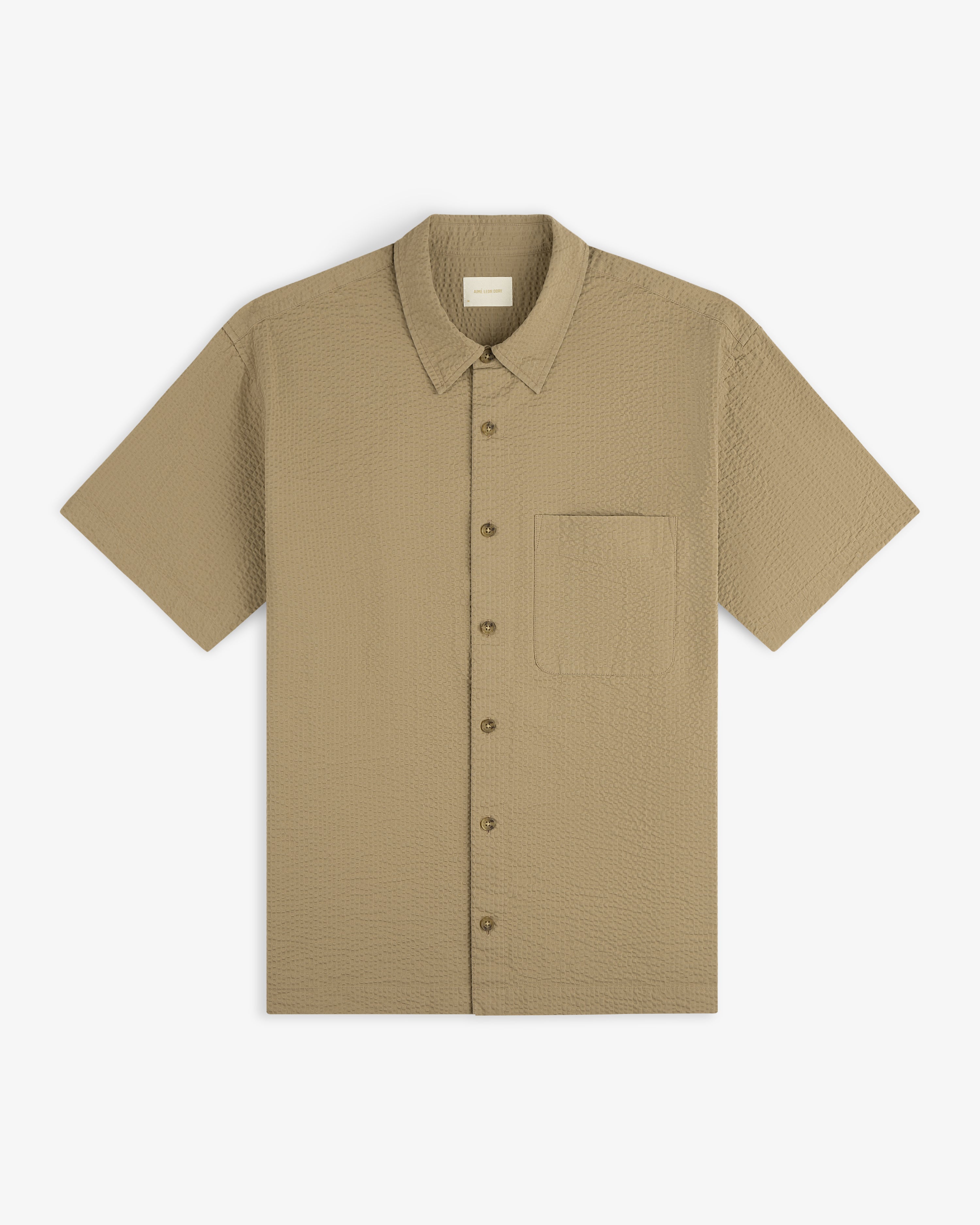 Short-Sleeve Seersucker Shirt in textured beige with front chest pocket, laid flat on a white background.