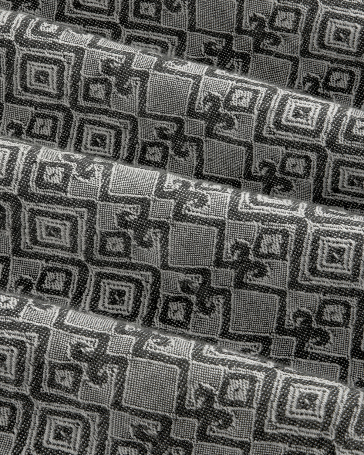 Jacquard Leisure Shirt in black and gray fabric features a geometric square pattern, shown with overlapping folds.
