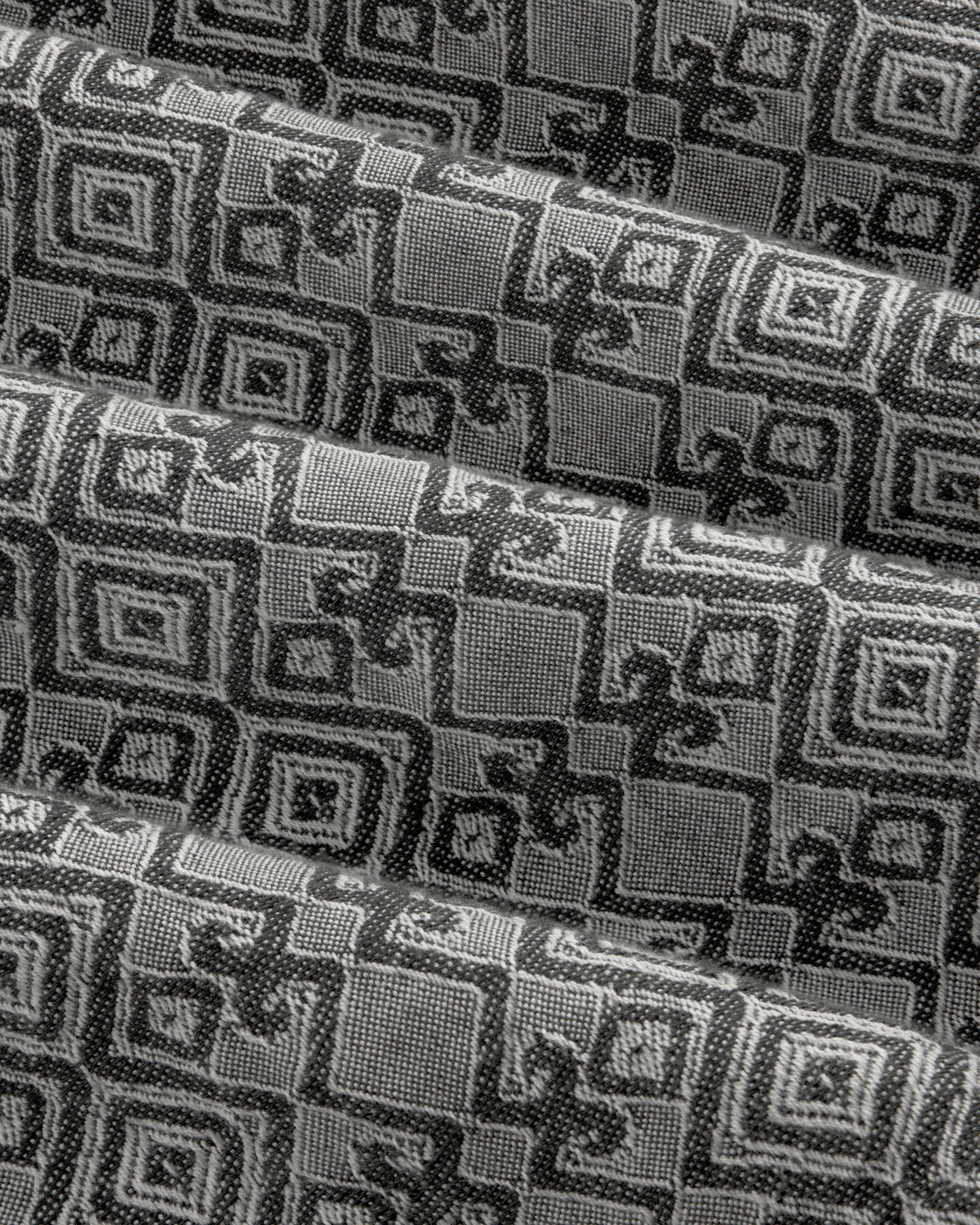Jacquard Leisure Shirt in black and gray fabric features a geometric square pattern, shown with overlapping folds.