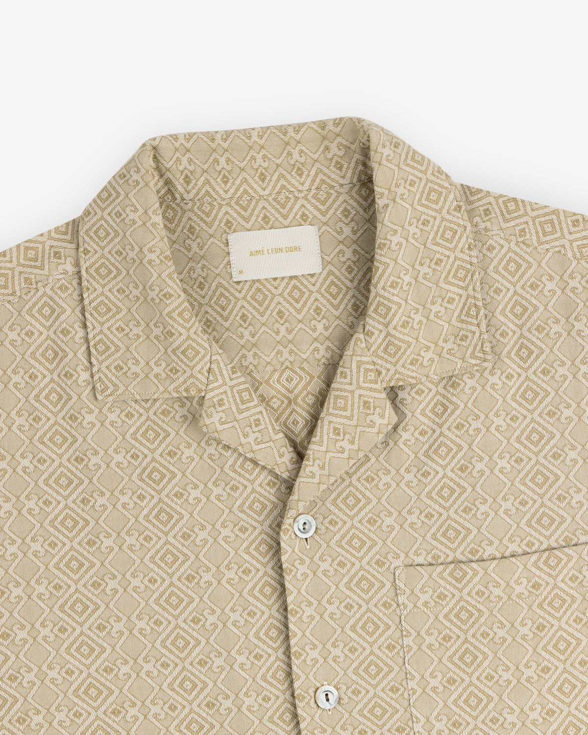 Jacquard Leisure Shirt—beige with geometric pattern, collar, chest pocket, and white buttons on a flat white background.