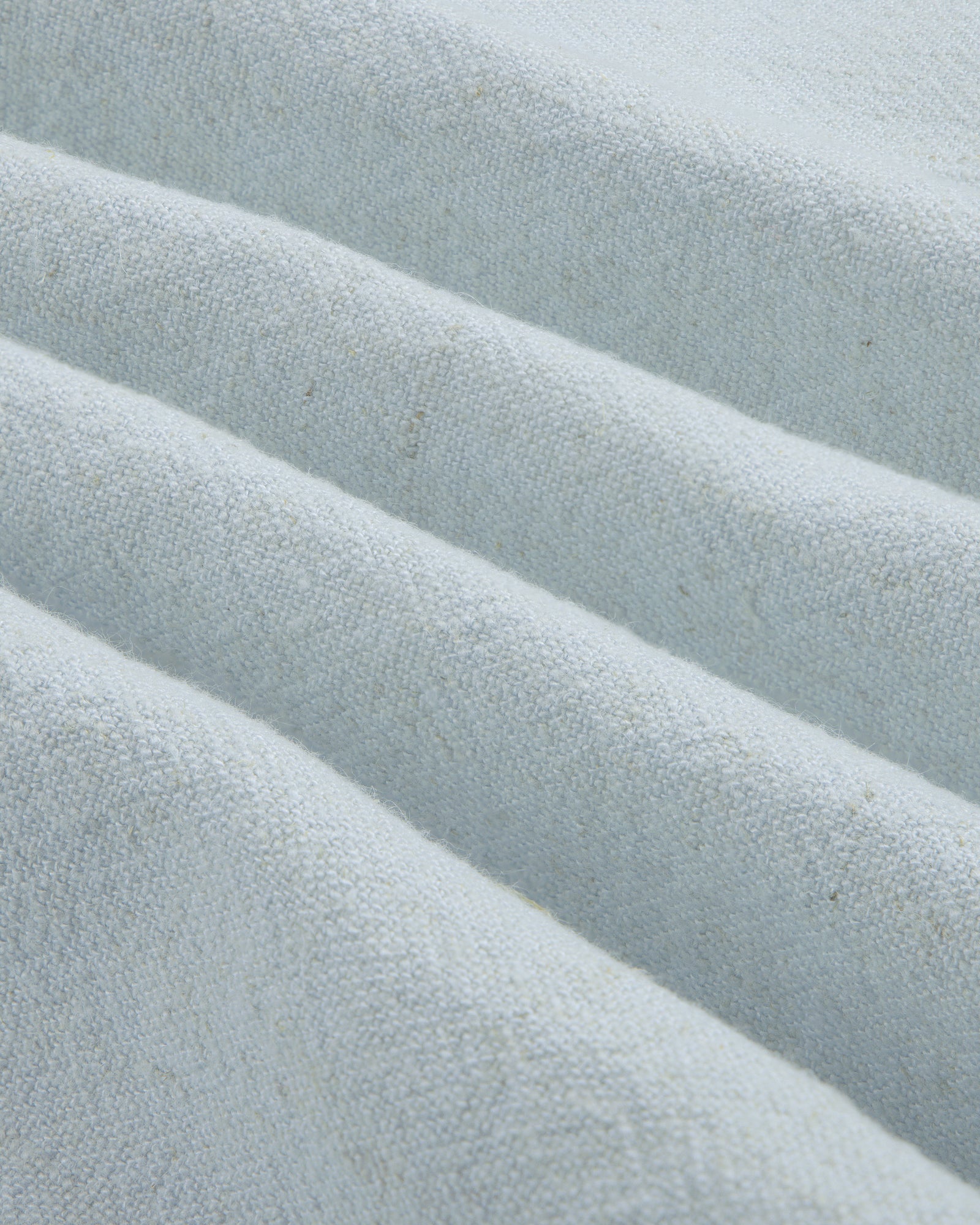 Close-up of the Linen Blend Leisure Shirt's textured light gray fabric with soft diagonal folds.