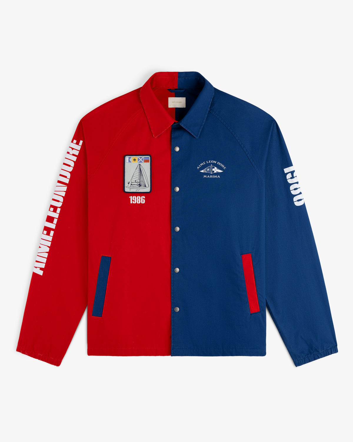 The Marina Jacket, half red and half blue with white text and patches, is laid flat on a white background.