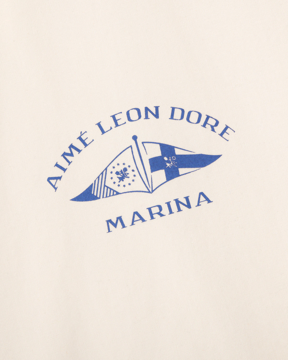 The Marina Jacket features a blue Aimé Leon Dore logo with two nautical flags on a cream background.
