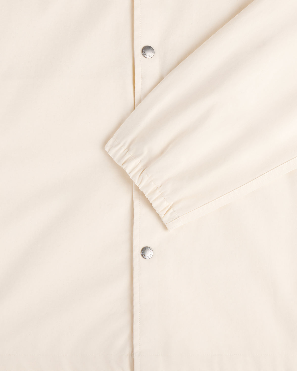 Close-up of the Marina Jacket in cream with silver snap buttons and elasticated sleeve cuffs.