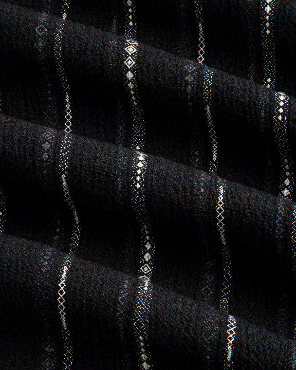 Close-up of black Cropped Jacquard Camp Shirt featuring vertical stripes and geometric patterns in white and gray.
