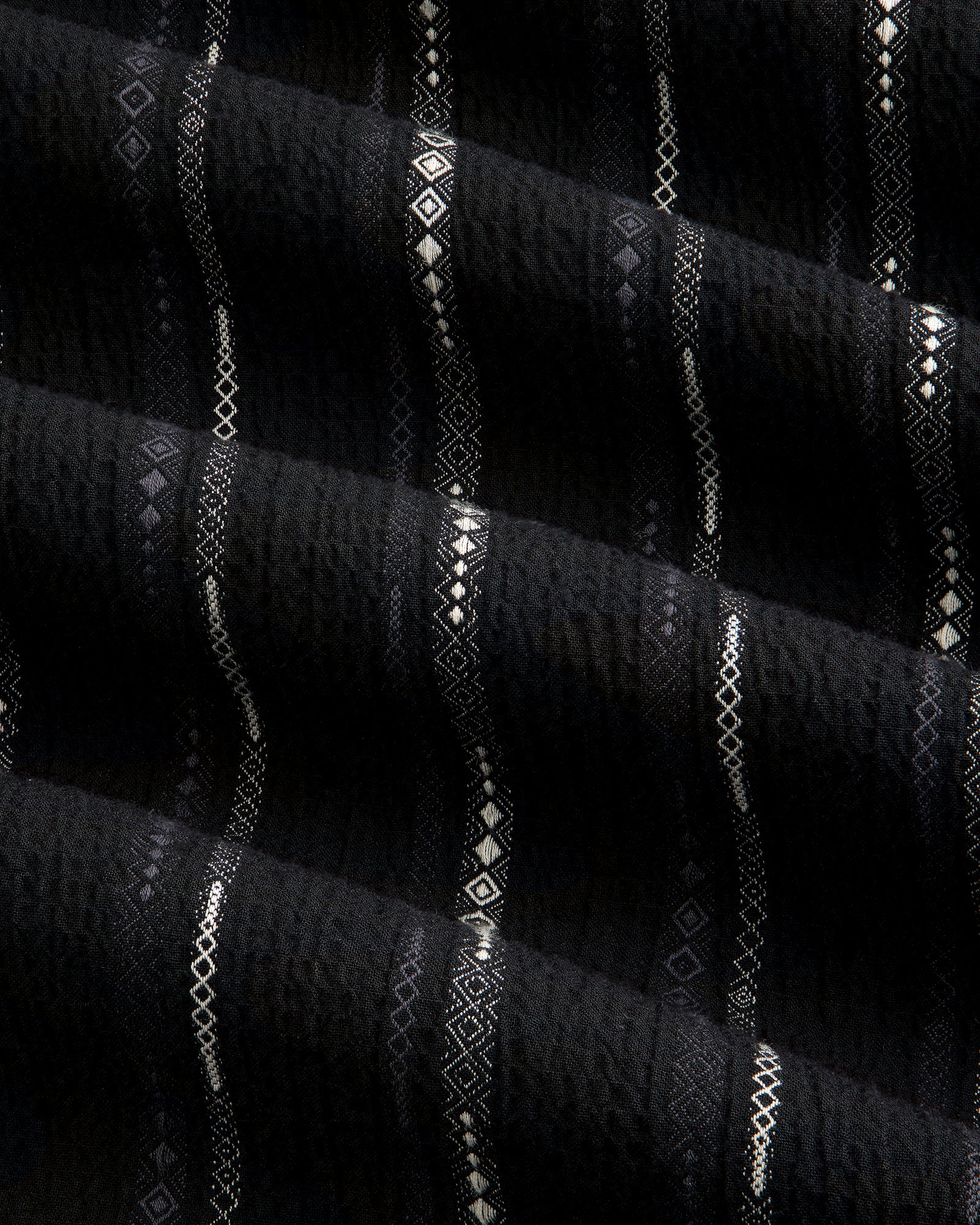 Close-up of black Cropped Jacquard Camp Shirt featuring vertical stripes and geometric patterns in white and gray.