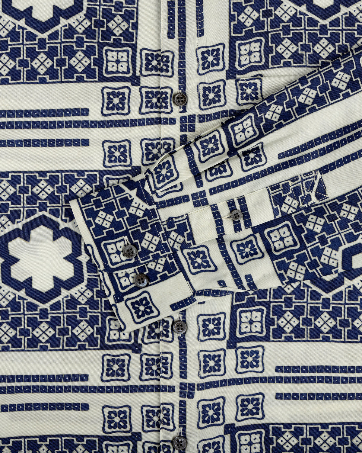 Close-up of the Mosaic Button Down Shirt with blue and white geometric patterns, buttons, and a folded cuff.