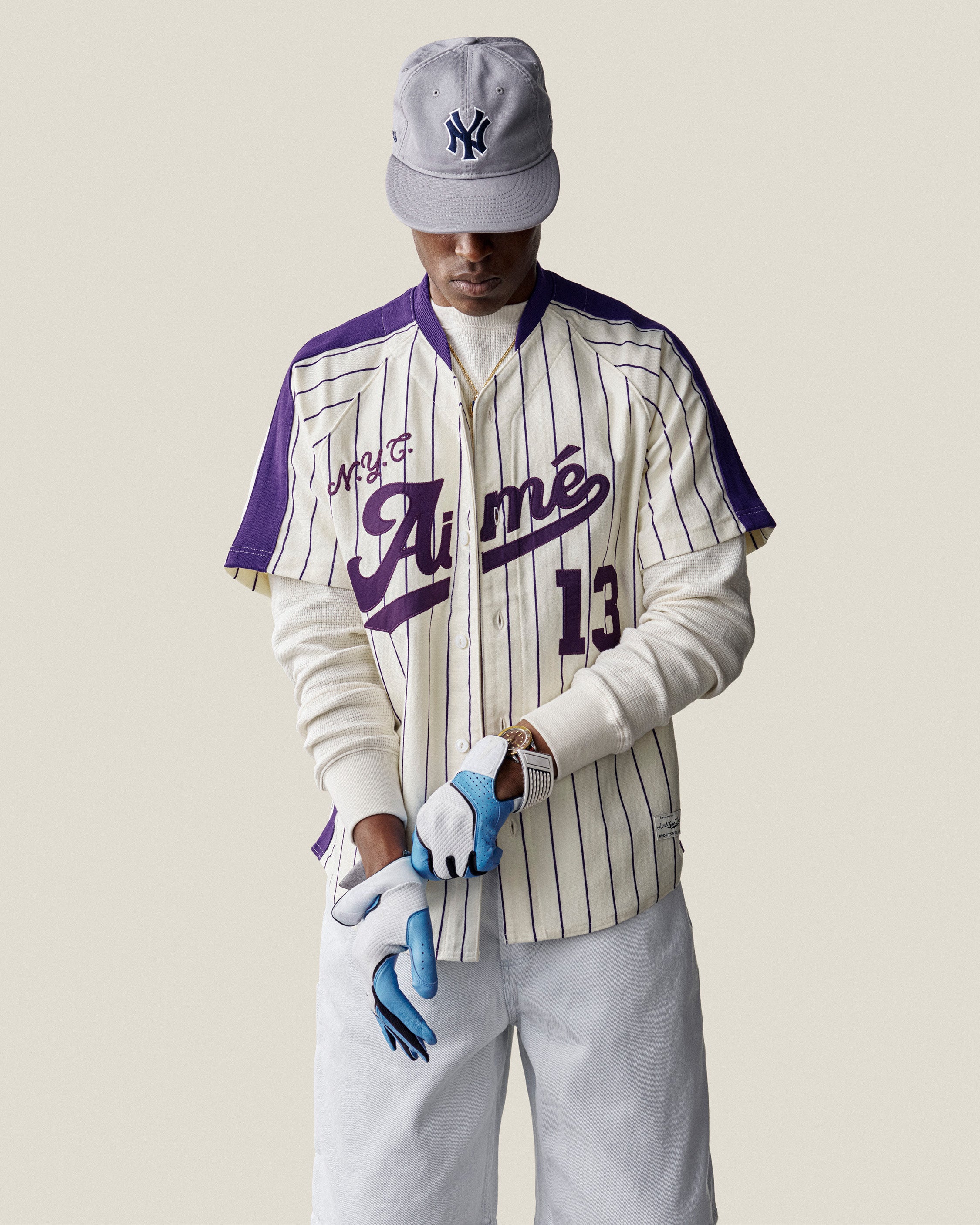 Man wearing a Long-Sleeve Waffle Thermal, gray NY cap, white pants, and blue gloves against a plain background.