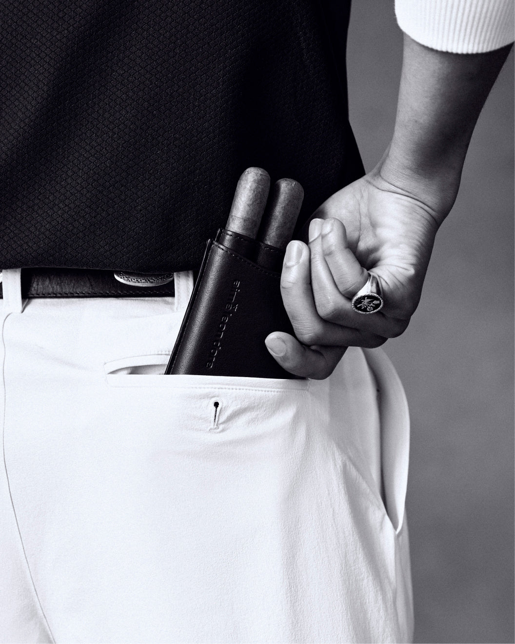 Someone slips the ALD Golf Leather Cigar Case holding two cigars into the pocket of white trousers.