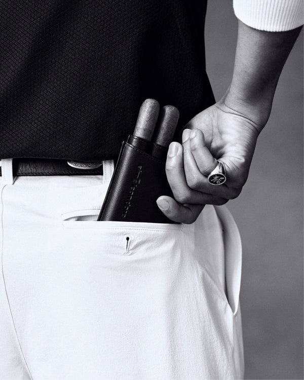 Someone slips the ALD Golf Leather Cigar Case holding two cigars into the pocket of white trousers.