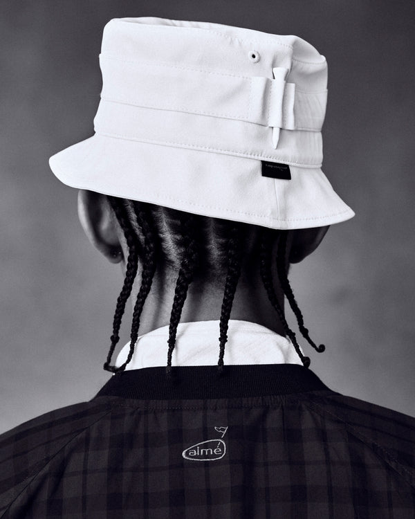Person with braided hair in an ALD Golf Bucket Hat and dark jacket, shown from behind against a plain background.
