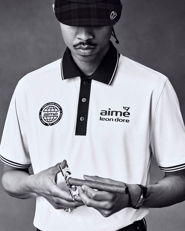 Black and white photo of a man in an ALD Golf Tour Polo, looking down and holding a watch.