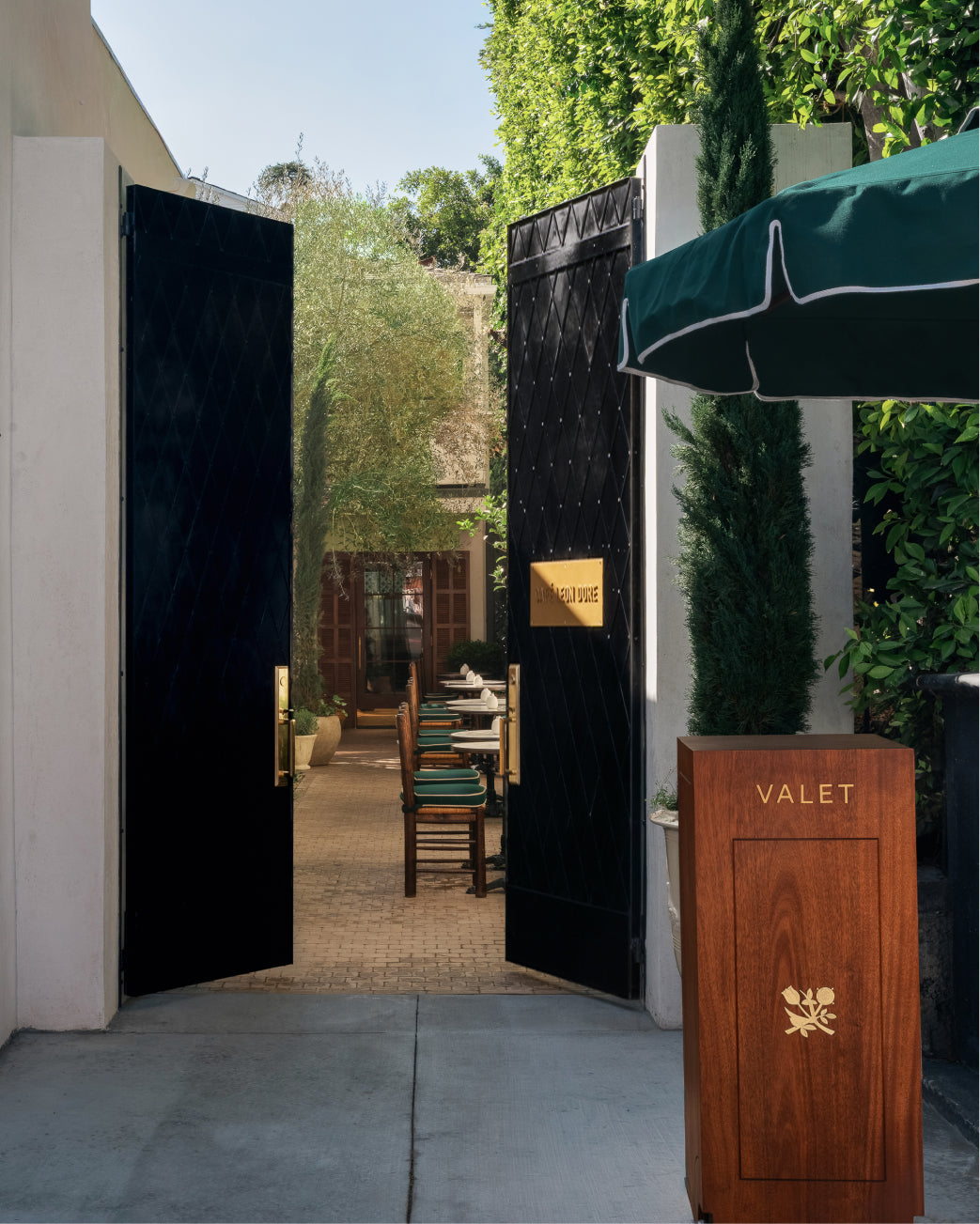 Open black doors leading to courtyard area with chairs and a Valet sign at Los Angeles flagship