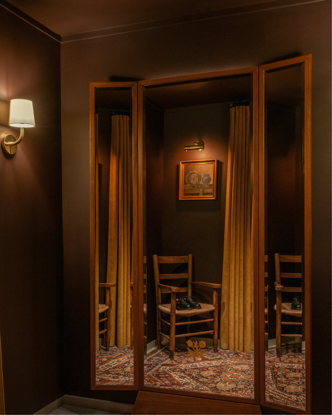 Dramatic interior scene with a large mirror reflecting a room with chairs and a painting.