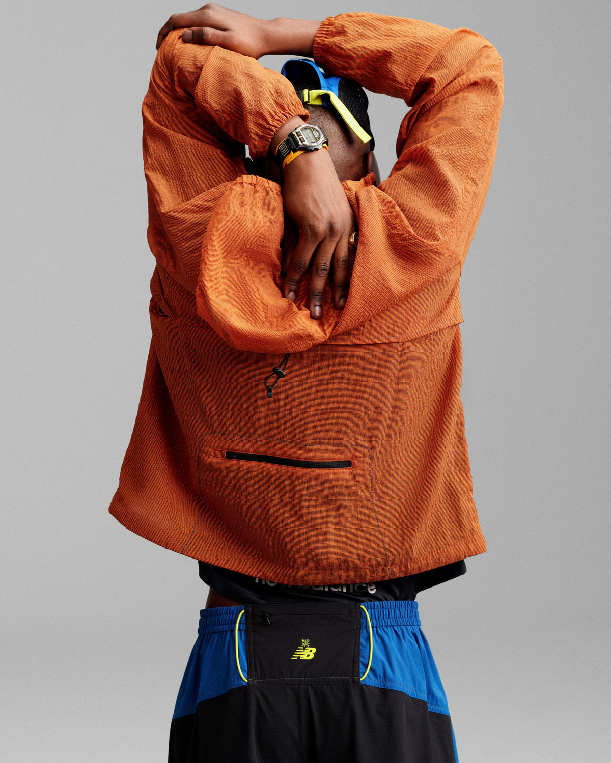 Person wearing the ALD / New Balance Breathable Half-Zip Pullover stretches with arms overhead, back to camera.