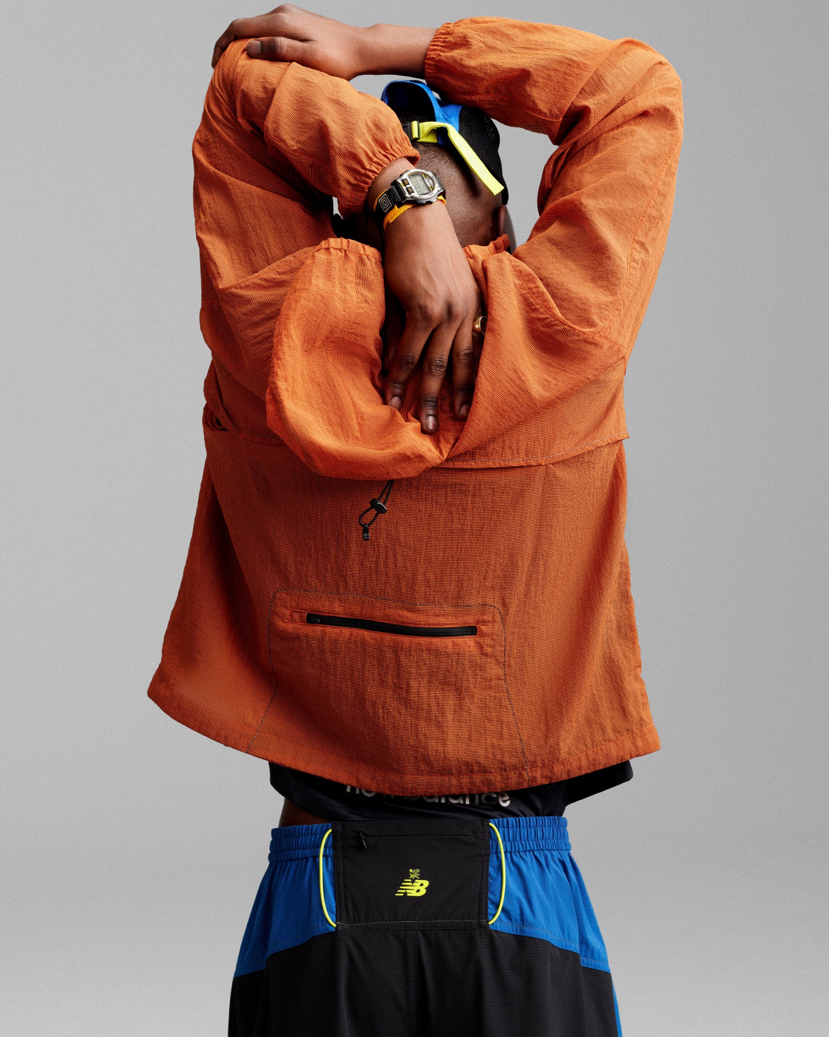 Person wearing the ALD / New Balance Breathable Half-Zip Pullover stretches with arms overhead, back to camera.