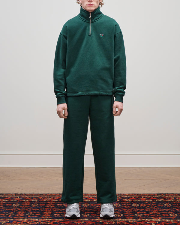 Person in a Crest Quarter Zip Pullover and gray sneakers stands on a patterned rug against a plain wall.