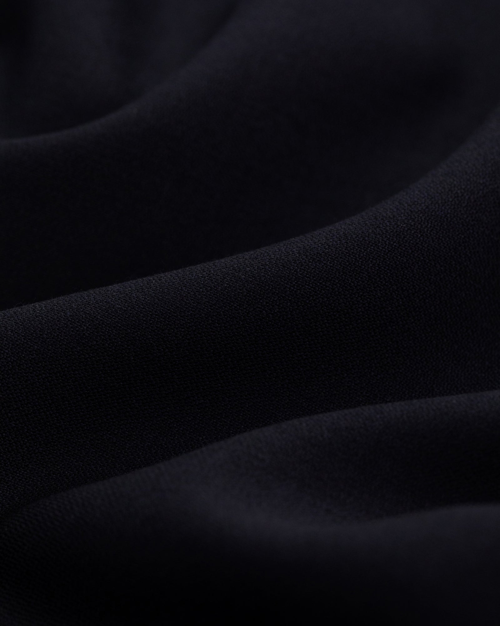 Close-up of the Tropical Wool Suit Jacket’s soft, dark fabric with gentle folds and smooth texture.