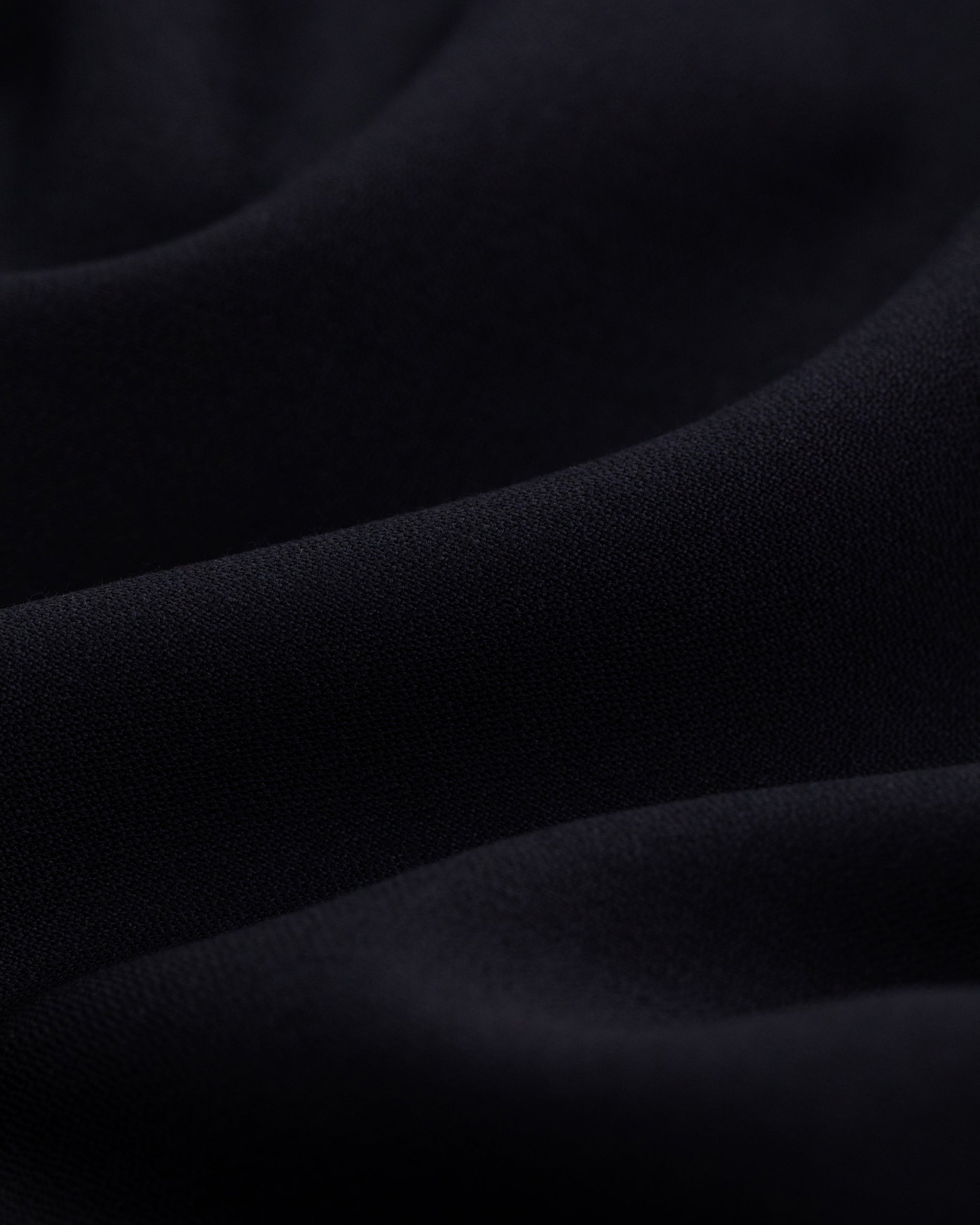 Close-up of the Tropical Wool Suit Jacket’s soft, dark fabric with gentle folds and smooth texture.